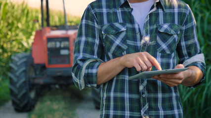 Portrait of a beautiful young farmer (student) working in the field with a tractor working in a...