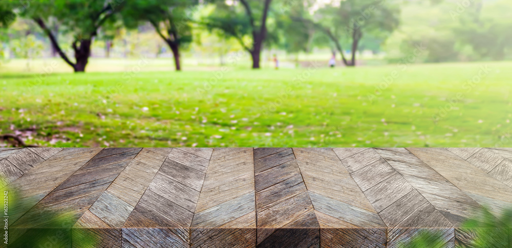Poster empty grunge wooden plank table top with blur park green nature bokeh and leaf foreground,mock up fo