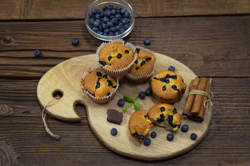 Muffins  with blueberries, chocolate and cinnamon on a wooden board