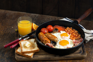 Full English breakfast on wooden table with orange juice