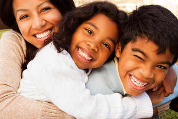 Biracial family laughing and smiling outside.