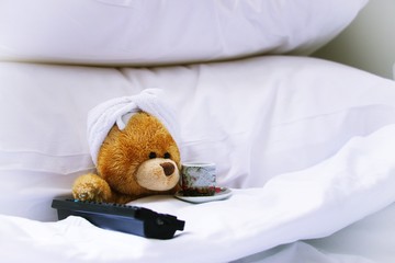 Lonely bear wears white towel on her head is sleeping on white pillow