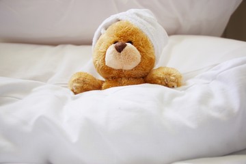 Lonely bear wears white towel on her head is sleeping on white pillow