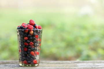 Cocktail with freshly picked berries/ glass cup with forest blueberries and strawberries on a table