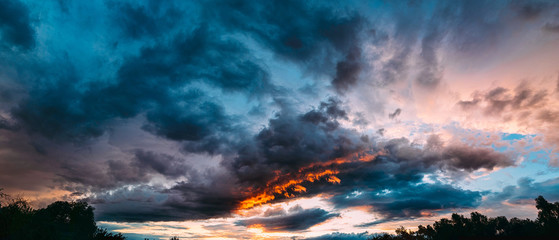 Panorama of dramatic colored blue, gray and orange sunset on beautiful sky. Sky background on sunset with clouds