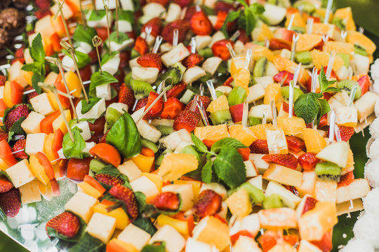 Catering for party and healthy food. Closeup of mix of various kinds of sliced fruit and vegetables with cheese on big tray. Horizontal color image.
