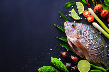 Vue de dessus de délicieux poissons frais et herbes et épices, citron, tomate, piment et divers légumes sur fond de bois sombre, espace pour la texture. Alimentation saine, régime alimentaire ou concept de cuisine.