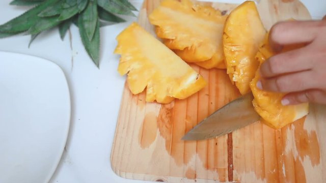 Close up shot hands of women using kitchen knife to cutting and peeling ripe pineapple shallow depth of field with ambient sound