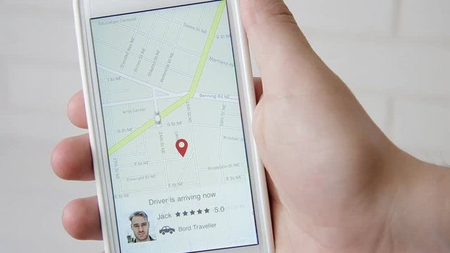 Interface of car sharing application. Man arrives to pick up his passenger. Man using application on the smartphone