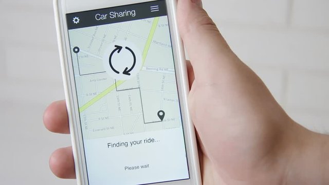 Man requests car using car sharing application on the smartphone and waits for the driver