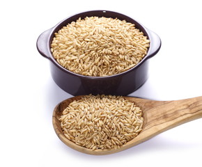 Oat grains in wooden spoon and purple porcelain cup, dish isolated on white background