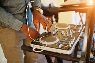 African american dj in huge white headphones creating music on mixing panel.