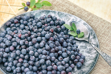 blueberries in a forged plate with a spoon on a wooden table