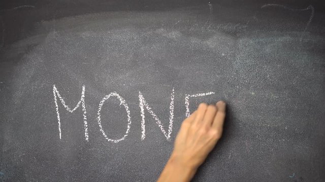 Woman's hand writing "MONEY" with white chalk on blackboard