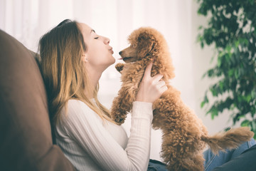 Young girl is resting with a dog on the armchair at home .