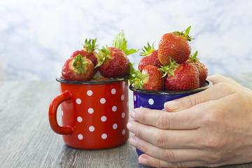 Bright ripe strawberry  in a metal cups  on a light background.