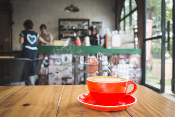 red coffee cup on wooden in coffee shop background