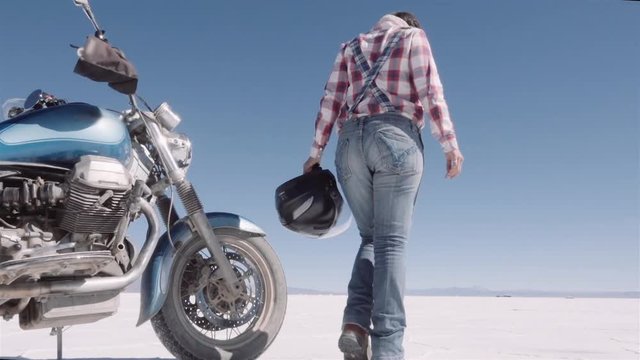 Female biker walks near the motorcycle, trip motorcycle adventure. Slow motion.