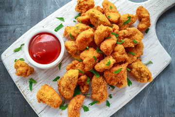 Fried crispy chicken nuggets with ketchup on white board