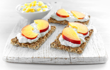 Homemade Crispbread toast with Cottage Cheese and nectarine on white wooden board.