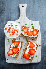 Homemade Crispbread toast with Cottage Cheese and Strawberry on white wooden board.