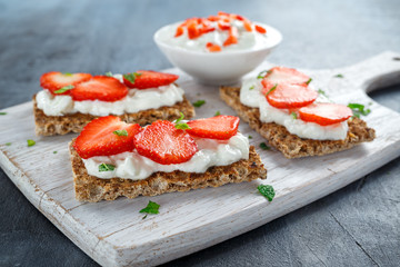 Homemade Crispbread toast with Cottage Cheese and Strawberry on white wooden board.