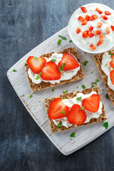 Homemade Crispbread toast with Cottage Cheese and Strawberry on white wooden board.