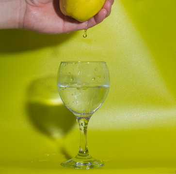 glass water drops fall from the hands with yellow Apple.