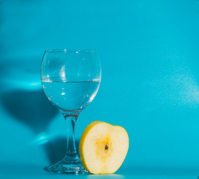 on a blue background and a slice of yellow Apple with a glass of water.