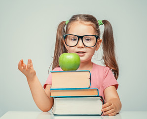 beautiful cute little girl counting on fingers behind the books