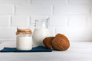 Coconut milk on white wooden kitchen table. Copy space.