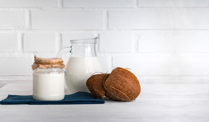 Coconut milk on white wooden kitchen table. Copy space.