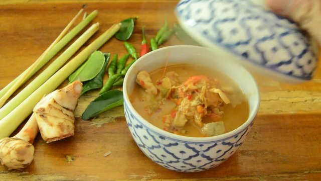 spicy shrimp tom yum soup in bowl and hand open cover with smoke floating