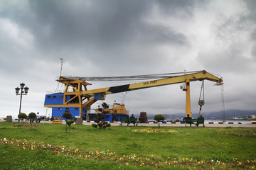 Sea port in Batumi, Georgia, with green lawn of embankment and big yellow crane on cargo ship