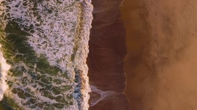 A view of the waves arriving at the beach and leaving a wet track on the sand.