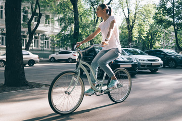 Slim woman in jeans and a T-shirt rides around town on a bicycle