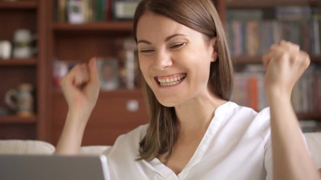 Businesswoman using laptop at home, professional female recieving good news excited cheerful smiling