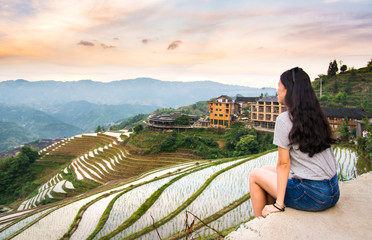 Fototapeta na wymiar Girl enjoying sunset at terraced rice field in Longji, China