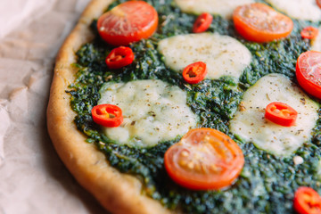 Appetizing pizza with pesto mozzarella and cherry and chili peppers