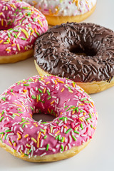 Tasty donuts with colorful sprinkles on light background