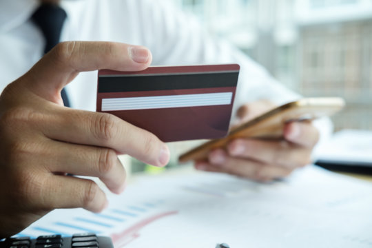 Close-up image of asian business man hands holding credit card and using digital tablet smart phone.Paying with credit card when shopping online. Online shopping concept