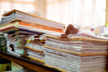 Close up paper stack on the desk related to business functions.Stack of business document files,report paper of accounting and financial with morning light,soft focus