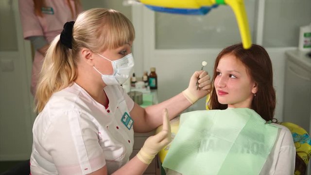 Dentist talking with young patient. Young girl attending dentist. Beautiful blonde female dentist. Conversation between dentist and child.