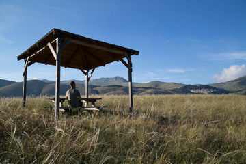 Hiker sits at a picnic table with beautiful panorama, National park Gran Sasso and Monti della Laga, Italy