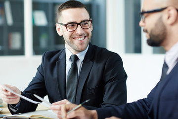 Happy employer looking at business partner during talk