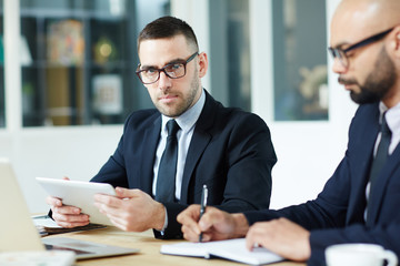 Serious businessman in eyeglasses and his colleague planning work