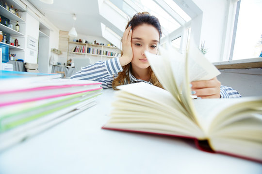 Reluctant Girl Sitting In Library And Preparing Report For Seminar