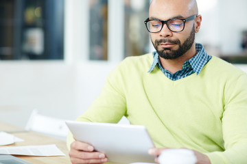 Serious young businessman reading online data