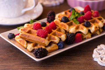 Belgium waffles with raspberries, chocolate and syrup on a plate.