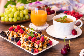 Belgium waffles with raspberries, chocolate and syrup on a plate.